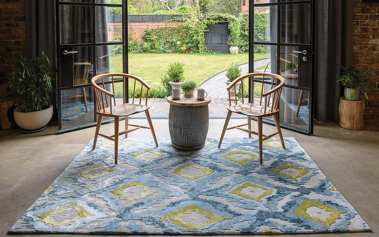 Multi coloured bespoke rug on a stone tiled floor in front of open patio doors overlooking a garden.