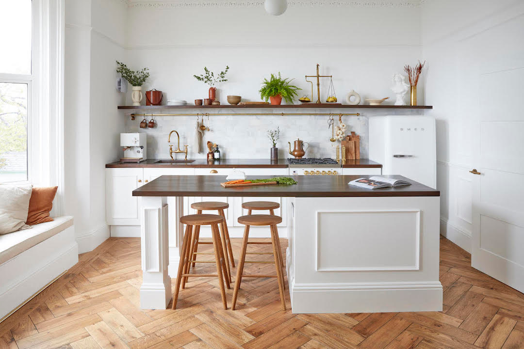 Simply Bespoke Collection flooring in a traditional style kitchen space with white fronted units and wooden bar stools.