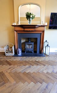 Simply Bespoke Collection flooring in a traditional style living space with a wooden fireplace surround and wood burning stove.