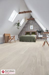 Light coloured Karndean Knight Tile Grey Scandi Pine flooring in a contemporary style attic bedroom with an exposed stone feature wall.
