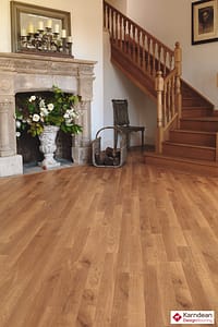 Mixed tan coloured Karndean Da Vinci Light Oak flooring in a traditional style room featuring a stone fireplace and wooden stair case.