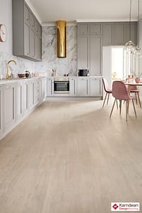 Light coloured Karndean Opus Coastal Sawn Oak flooring in a modern style kitchen dinner with ivory coloured units and a wooden table with chairs.