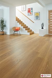 Light tan coloured Karndean Van Gogh Golden Brushed Oak flooring in a modern style living space with white walls and an open staircase.