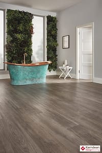 Darker coloured Karndean Van Gogh Nimbus Oak flooring in a traditional style living space featuring a turquoise coloured roll top bath tub.