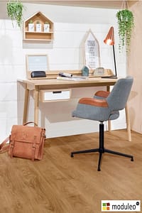 Moduleo Laurel Oak 51822 flooring in a modern style home office with a simple wooden table and office style chair.