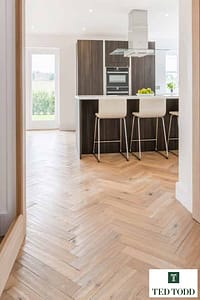 Light tan Coloured Ted Todd Raw Cotton European Oak flooring with a herringbone pattern in a modern kitchen setting.