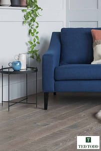 Ted Todd Amberley European Oak flooring, in a contemporary living room setting under a royal blue low backed sofa with wooden legs.