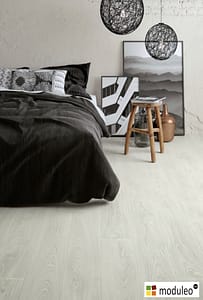 Moduleo Laurel Oak 51102 flooring in a modern style bedroom with black and white furnishings.