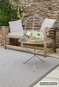 Light grey coloured Unnatural Flooring Boston rug in a contemporary patio setting featuring a wooden bench seat and metal framed coffee table.