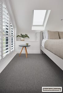 Dark grey Unnatural Flooring NY9001 New York carpet in a contemporary style bedroom featuring a small round wooden table and bed under a skylight.