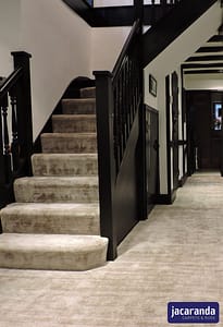 Light coloured Jacaranda Santushti Starlight carpet in a traditional style residential hallway and dark wood staircase.