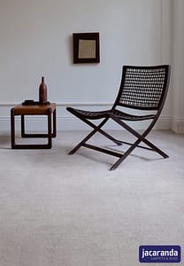 Light grey Jacaranda Chennai Sparrow carpet under a wooden slatted deck chair and side table.