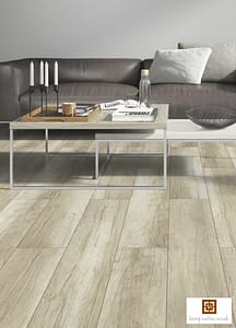 Light coloured V4 Hammer Beam Oak laminate flooring in a modern living space with a grey low backed leather sofa and two metal framed nesting coffee tables.