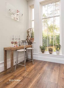 Mixed brown coloured Ted Todd Classic Crafted Textures Wiston flooring in a contemporary style room with a wooden bench table and two grey metal stools.