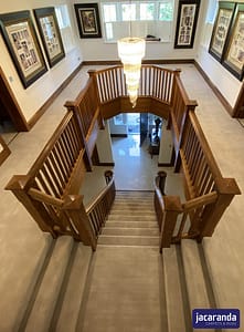 Light tan coloured Jacaranda Willingdon Vellum carpet in a large traditional style residential upper landing area with dark wood banister rails.