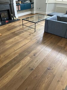 Simply Bespoke Collection flooring in a contemporary style living space with rectangular metal framed coffee table with a glass top, in front of a low level blue sofa.