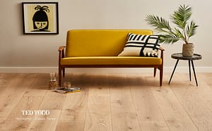 Tan coloured Ted Todd Classic Tones Hollington flooring in a living room setting with a low backed mustard coloured sofa with wooden legs and matching side table.