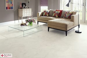 Light coloured Karndean Art Select Stone Fiore flooring in a contemporary style living room featuring a low backed corner sofa and a rectangular glass topped coffee table.