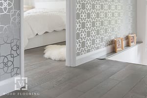 Dark coloured V4 Eiger Petit laminate flooring in a modern bedroom with silver wallpaper.