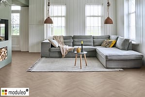 Moduleo Laurel Oak 51937 flooring in a contemporary style living room with a large grey low backed corner sofa.