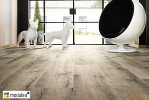 Moduleo Mountain Oak 56870 flooring in a modern style living space with white dog sculptures and a white pod chair in front of French doors leading to a garden space.