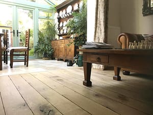 Simply Bespoke Collection flooring in a traditional style living space and conservatory with a large wooden dresser and low level wooden coffee table.
