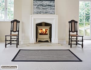 Unnatural Flooring Sebago fitted Jefferson rug in front of a traditional style mantle containing a wood burning stove, and flanked by matching wooden chairs.